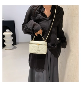 Detail of cream quilted crossbody bag with gold chain strap and double zipper closure