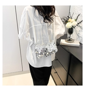 Silver sequin handbag with chain strap styled on a white shirt in a modern setting