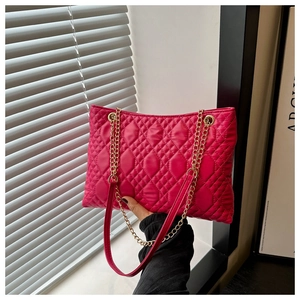 Macro detail of magenta quilted tote bag with diamond pattern and gold chain strap
