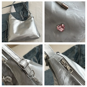 Detail view of silver pleated metallic tote with pink heart rhinestone and chain strap
