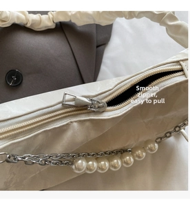 Détail de la fermeture éclair fluide et de la chaîne de perles sur le sac beige