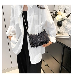 Detail of a chic black sequined crossbody bag with silver chain strap on a female model