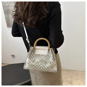 Detail view of ethnic embroidery bucket bag with wooden handle and landscape pattern