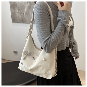 Close-up of white bow shoulder bag with pearls and rhinestone ribbon detail
