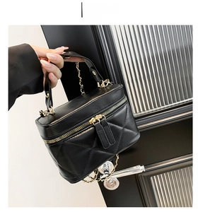 Detail of black quilted mini bag featuring gold chain handle and dual zipper closure