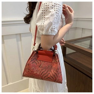 Detailed close-up of vintage red brocade handbag featuring traditional Chinese cloud patterns
