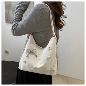 Detail of white marble-patterned tote bag featuring sparkling butterfly and pearl charms