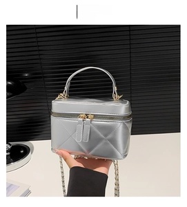 Detail of silver quilted bucket bag with top handle and chain strap for women