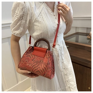 Detail of red jacquard bucket bag with traditional cloud patterns and wooden handle