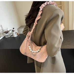 Detailaufnahme der rosa Falten-Tasche mit eleganter Perlenkette und Metallkettendetail