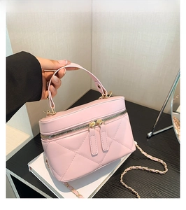 Detail of pink quilted PU leather cosmetic bag with double zippers and metal chain strap