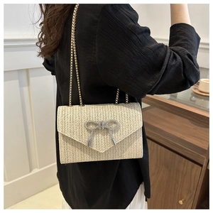 Détail du sac en paille tressée avec papillon en strass et bandoulière en chaîne dorée