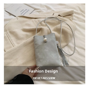 Detail of light gray crossbody phone bag with pearl buckle, fringe and silver chain