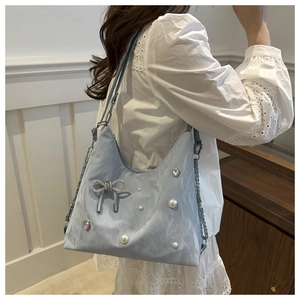 Detail of light blue wrinkled tote with metallic bow, white pearls and chain strap