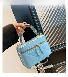 Detail of light blue quilted crossbody bag with gold chain strap and double zip closure