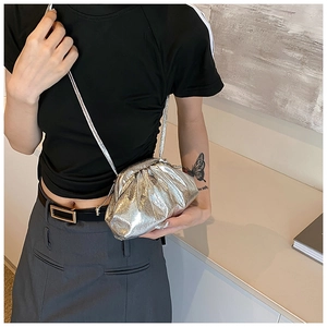 Detail of silver metallic pleated cloud bag with slim shoulder strap on model
