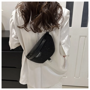 Detail of black rhinestone crescent crossbody bag worn over a white blazer