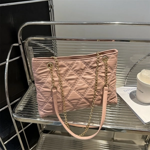 Pink quilted leather tote bag with gold chain strap displayed on a metallic shelf