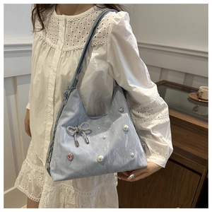 Detail view of light blue shoulder bag with silver rhinestone bow and pearl charms