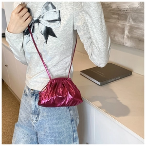 Détail du sac nuage plissé rose métallisé avec fine bandoulière porté par un mannequin