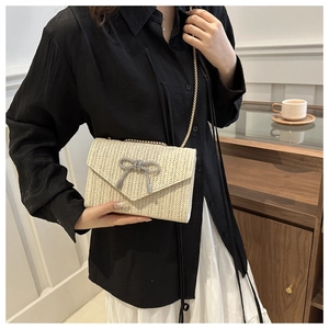 Détail d'un sac tressé beige avec un nœud en strass scintillant et une chaîne dorée