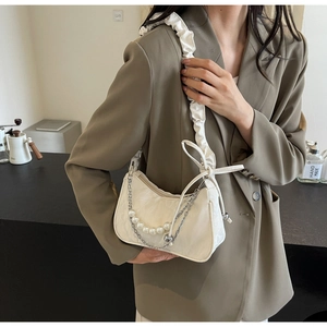 Detail der cremefarbenen Tasche mit gerafftem Schultergurt und Perlenkette Dekor