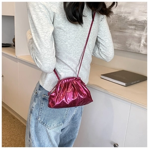 Close-up of a metallic plum-colored pleated crossbody cloud bag with a glossy finish