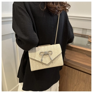 Détail du sac en paille avec nœud en strass et chaîne en métal sur un mannequin
