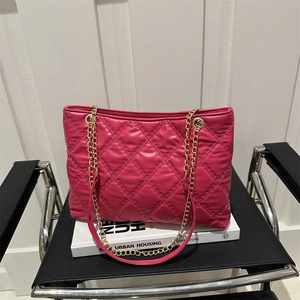 Hot pink quilted tote bag with golden chain strap on a chair, stylish 2024 fashion