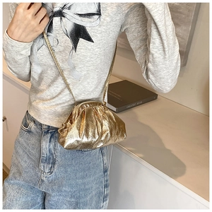 Detail of a chic metallic gold pleated shell bag featuring a thin shoulder strap design