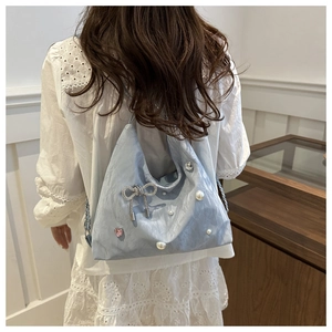 Blue pleated tote bag with silver butterfly pendant and pearls shown on a model