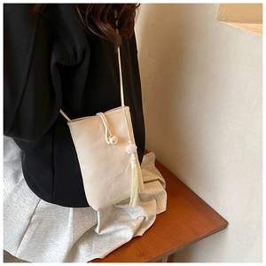 Dettaglio mini borsa a tracolla crema con bottone di perla e nappa laterale
