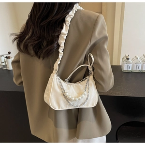 Gros plan sur sac à bandoulière plissé blanc avec perles et détail de chaîne en métal