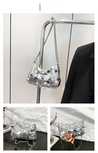 Detail view of a silver sequin crossbody bag featuring a fine metal chain strap