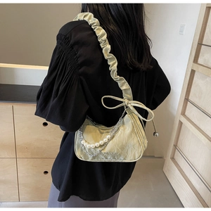Detail of pistachio green pleated shoulder bag with pearl chain and bow strap design