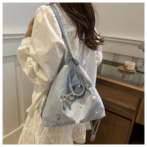 Detail of light blue pleated handbag featuring pearl accents and rhinestone bow charm