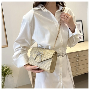 Détail d'un sac à bandoulière en paille avec nœud en strass et chaîne dorée fine