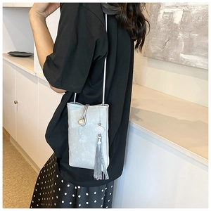 Détail du mini sac bandoulière gris clair avec boucle perle et longs pompons