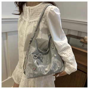 Detail of silver crescent shoulder bag featuring pearl accents and crystal heart bow