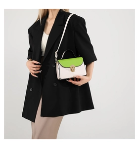Detail of cream and neon green contrast crossbody bag worn with a black blazer