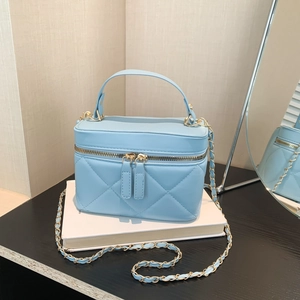 Light blue quilted leather crossbody bag with gold chain strap on a white book surface