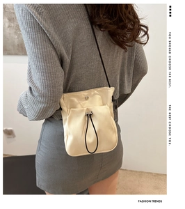 Minimalistische crème crossbody telefoontas met zwart koord gedragen door een model