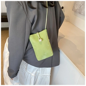 Dettaglio mini borsa a tracolla verde chiaro con chiusura a perla e finitura scamosciata