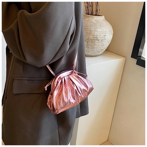 Detail of a shiny metallic pink pleated dumpling bag with slim leather cord shoulder strap
