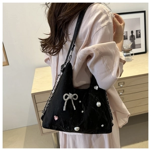 Detail of satin tote bag featuring metallic bow and pearl accents on the shoulder strap