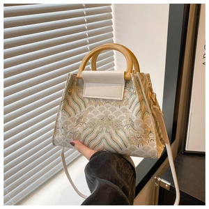 Detail of vintage embroidered bucket bag featuring round handles and ornate wave patterns