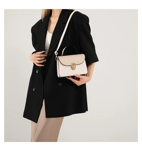 Detail of elegant beige crossbody bag with gold twist lock and smooth texture on a model