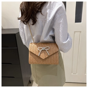 Détail du sac de plage tissé avec papillon en strass et bandoulière en chaîne
