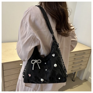 Close-up of black textured underarm bag with white pearls and a rhinestone bow detail