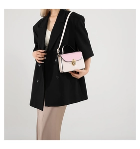Detail of soft leather crossbody bag with pink flap and gold circular twist lock clasp
